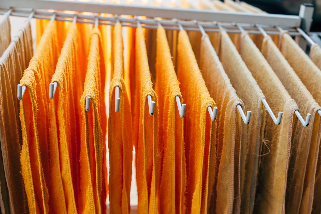 Vibrant orange and beige towels neatly hang on a drying rack indoors.